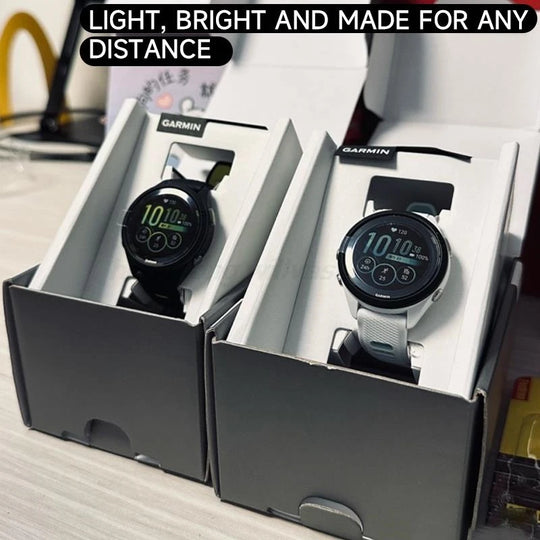 Two Garmin Forerunner 265 smartwatches in display boxes, one with a black band and one with a white band